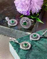 plata joyería conjunto con esmeraldas y diamantes en un verde mármol antecedentes foto