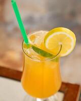 Refreshing orange juice being poured into glass with ice, lemon, lime and green straw photo