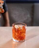 Bartender spraying on cocktail garnish with atomizer in bar setting photo