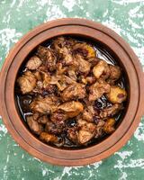 Delicious beef stew with cranberry sauce cooking in clay pot photo