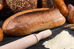 Fresh loaves of bread with flour wheat and gluten on a dark background photo
