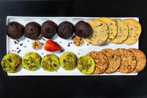 Tasty colorful chocolate cookies on the black background, top view photo