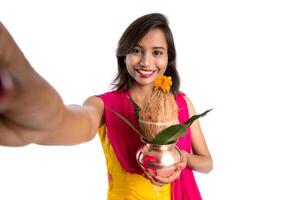 Beautiful young happy girl taking selfie with Kalash using a camera or smartphone on a white background photo