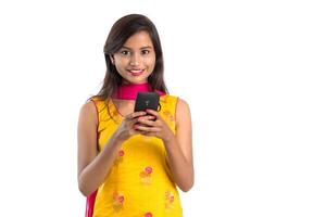 Young Indian girl using a mobile phone or smartphone isolated on a white background photo