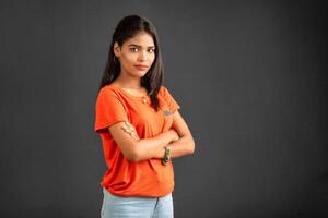Portrait of a beautiful, smiling, young girl posing with hands-folded on gray background. photo