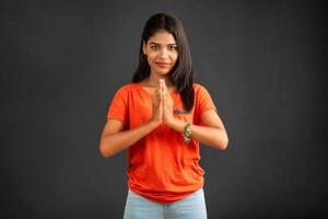 Beautiful Indian girl with welcome expression or inviting or greeting Namaste on a grey background. photo