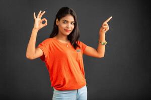 Portrait of a successful cheerful young girl pointing and presenting something with hand or finger with a happy smiling face. photo