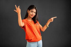 Portrait of a successful cheerful young girl pointing and presenting something with hand or finger with a happy smiling face. photo