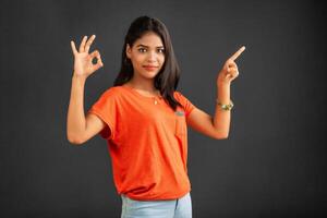 Portrait of a successful cheerful young girl pointing and presenting something with hand or finger with a happy smiling face. photo