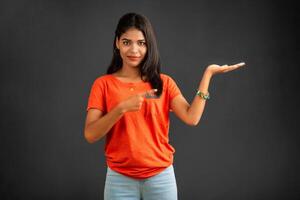 Portrait of a successful cheerful young girl holding and presenting something on hand with a happy smiling face. photo