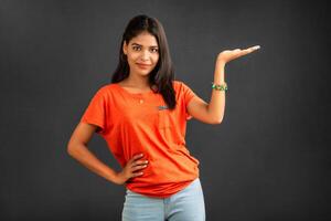 Portrait of a successful cheerful young girl holding and presenting something on hand with a happy smiling face. photo