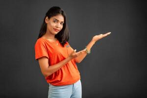 Portrait of a successful cheerful young girl holding and presenting something on hand with a happy smiling face. photo