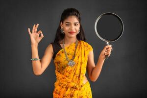 Young girl holding and posing with kitchen utensils pan on a grey background photo