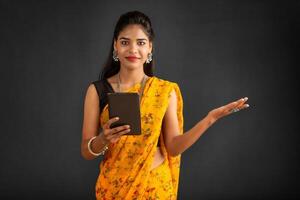 Young beautiful girl or woman holding and using smartphone or mobile or tablet phone on a grey background photo