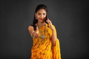 Young beautiful girl or woman holding and using smartphone or mobile or tablet phone on a grey background photo