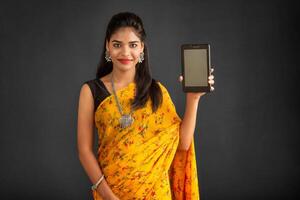 Young beautiful girl showing a blank screen of a smartphone or mobile or tablet phone photo