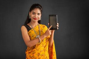 Young beautiful girl showing a blank screen of a smartphone or mobile or tablet phone photo