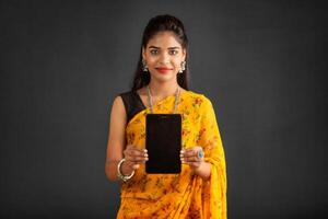 Young beautiful girl showing a blank screen of a smartphone or mobile or tablet phone photo