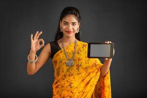 Young beautiful girl showing a blank screen of a smartphone or mobile or tablet phone photo