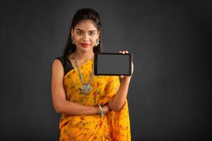 Young beautiful girl showing a blank screen of a smartphone or mobile or tablet phone photo