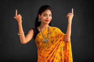Portrait of a successful cheerful young girl pointing and presenting something with hand or finger with a happy smiling face. photo