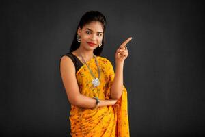Portrait of a successful cheerful young girl pointing and presenting something with hand or finger with a happy smiling face. photo