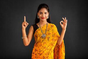 Portrait of a successful cheerful young girl pointing and presenting something with hand or finger with a happy smiling face. photo