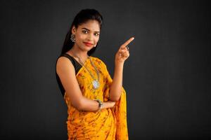 Portrait of a successful cheerful young girl pointing and presenting something with hand or finger with a happy smiling face. photo