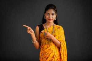 Portrait of a successful cheerful young girl pointing and presenting something with hand or finger with a happy smiling face. photo