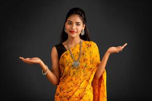 Portrait of a successful cheerful young girl holding and presenting something on hand with a happy smiling face. photo