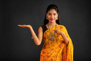 Portrait of a successful cheerful young girl holding and presenting something on hand with a happy smiling face. photo