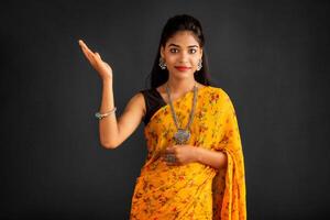 Portrait of a successful cheerful young girl holding and presenting something on hand with a happy smiling face. photo