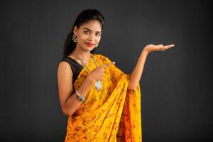 Portrait of a successful cheerful young girl holding and presenting something on hand with a happy smiling face. photo