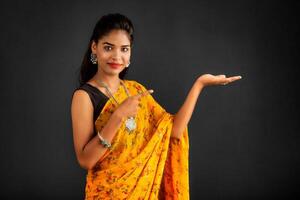 Portrait of a successful cheerful young girl holding and presenting something on hand with a happy smiling face. photo