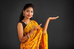 Portrait of a successful cheerful young girl holding and presenting something on hand with a happy smiling face. photo
