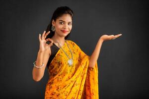 Portrait of a successful cheerful young girl holding and presenting something on hand with a happy smiling face. photo