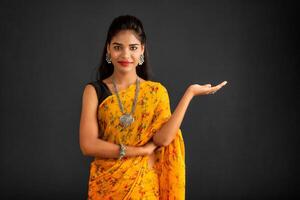 Portrait of a successful cheerful young girl holding and presenting something on hand with a happy smiling face. photo