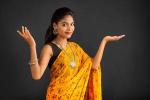 Portrait of a successful cheerful young girl holding and presenting something on hand with a happy smiling face. photo