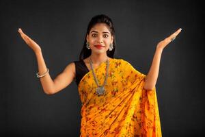Portrait of a successful cheerful young girl holding and presenting something on hand with a happy smiling face. photo