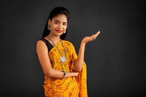 Portrait of a successful cheerful young girl holding and presenting something on hand with a happy smiling face. photo