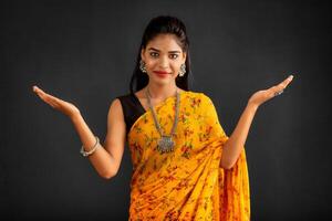 Portrait of a successful cheerful young girl holding and presenting something on hand with a happy smiling face. photo