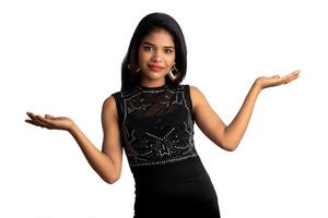 Portrait of a successful cheerful young girl pointing and presenting something with hand or finger with a happy smiling face. photo