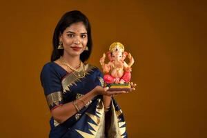 Happy young Indian woman posing with Ganesha statue on the occasion of Ganesh Festival photo