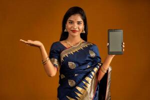 Young beautiful girl showing a blank screen of smartphone or mobile or tablet phone photo