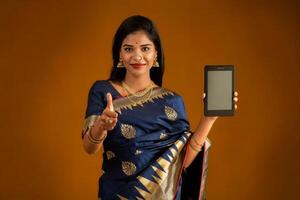 Young beautiful girl showing a blank screen of smartphone or mobile or tablet phone photo