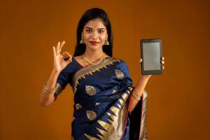 Young beautiful girl showing a blank screen of smartphone or mobile or tablet phone photo