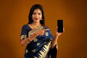 Young beautiful girl showing a blank screen of smartphone or mobile or tablet phone photo