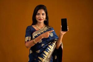 Young beautiful girl showing a blank screen of smartphone or mobile or tablet phone photo