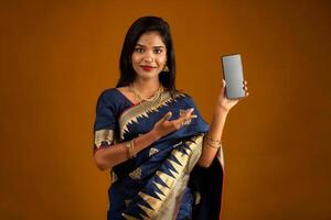 Young beautiful girl showing a blank screen of smartphone or mobile or tablet phone photo