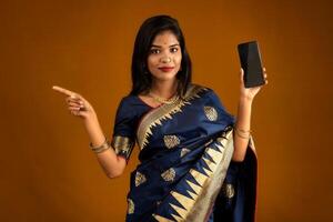 Young beautiful girl showing a blank screen of smartphone or mobile or tablet phone photo
